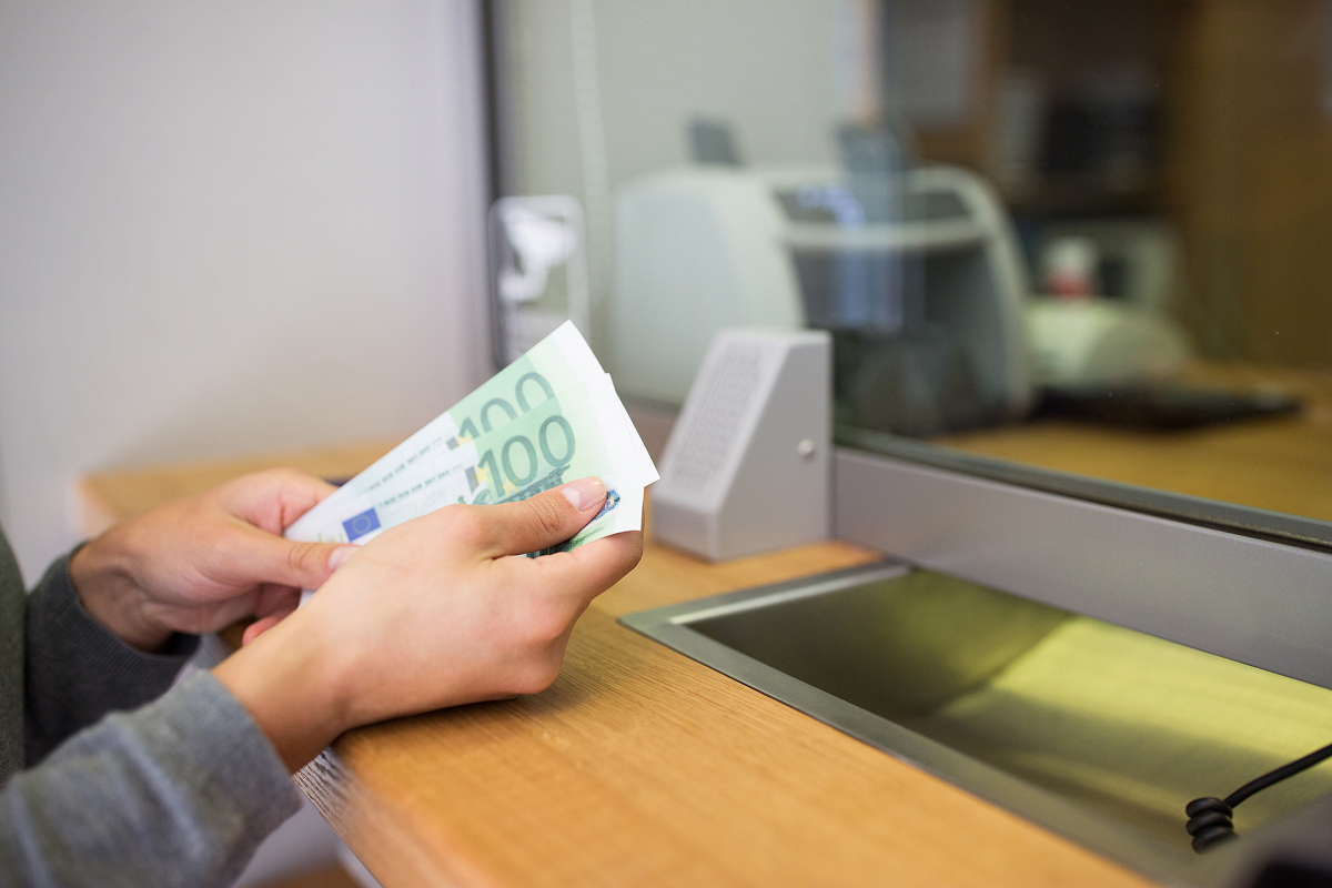 A woman's hands holding some cash at a counter