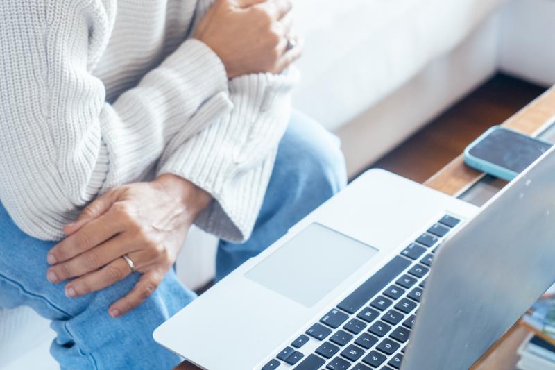 A woman with a stomach ache looking at a laptop